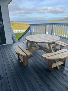 una mesa de picnic de madera y bancos en una terraza en Wasterview, Central Mainland, Ideal base en Lerwick