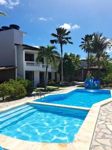 a pool in front of a house with palm trees at Pousada Neptun in Conde