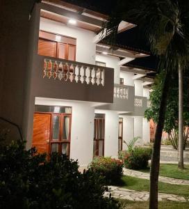 a large white building with a palm tree in front of it at Pousada Neptun in Conde