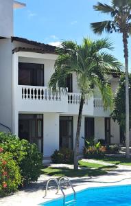 un edificio blanco con palmeras y piscina en Pousada Neptun en Conde