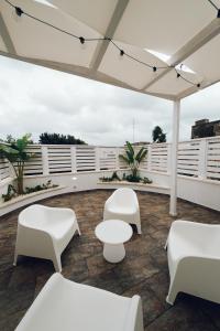 un patio con sillas blancas y mesas en el techo en Puro, en Mesagne