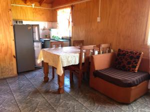 cocina con mesa, sillas y nevera en Cabañas melinka en Licán Ray