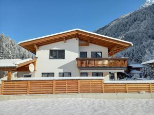 une maison avec un balcon dans la neige dans l'établissement Haus Blickfang, à Neustift im Stubaital