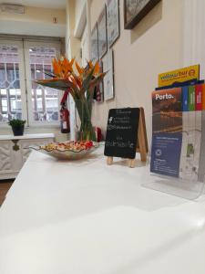 uma mesa com um vaso de flores e um cartaz em Clérigos Ville Porto Rooms no Porto