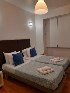 a bedroom with two beds with blue and white pillows at Clérigos Ville Porto Rooms in Porto +25 photos