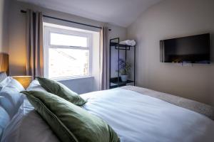 um quarto com uma cama branca com almofadas e uma janela em Dalton Sq Apartment 2 em Lancaster