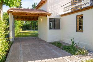 una entrada a una casa blanca con pérgola de madera en Luminosa casa abrazada por el verde en Mendoza en Luján de Cuyo