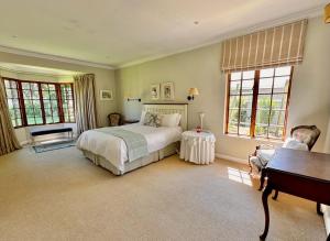 a bedroom with a bed and a desk and windows at Bourne View in Nottingham Road