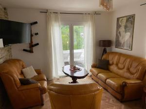 a living room with two leather couches and a table at Lexor Holiday Home in Tuzla