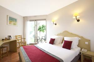 - une chambre avec un grand lit blanc et des oreillers rouges dans l'établissement Hôtel Paradou Avignon Sud, à Avignon