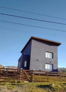 una casa con una valla delante de ella en Cedro Azul,casa loft en El Calafate