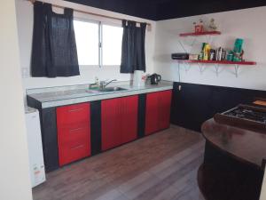 una cocina con armarios rojos y fregadero en Cedro Azul,casa loft en El Calafate