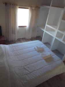 1 dormitorio con cama blanca y ventana en Cedro Azul,casa loft en El Calafate