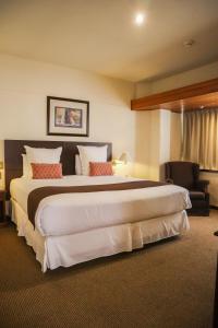 una habitación de hotel con una cama grande y una silla en J&A Classic Hotel, en Lima