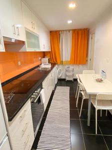 a kitchen with white cabinets and a white table and a table and chairs at Duplex Próximo do Aeroporto Lisboa in Lisbon