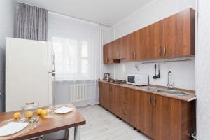 een keuken met houten kasten en een houten tafel bij Апартаменты на Сатпаева in Alma-Ata
