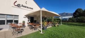 un restaurante con mesas y sillas bajo una sombrilla en Campanile Chambéry, en Chambéry