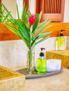 a vase with a flower and two bottles of soap at Ileverde 21 - Private garden Bungalow in Punta Cana
