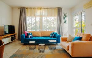 a living room with a blue couch and a tv at Appartements - Le Paradisier Ambatobe in Antananarivo