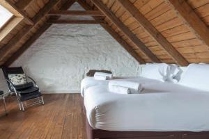 a attic bedroom with two beds and a chair at Isle of Skye Cottage in Kyleakin