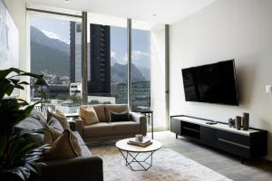 a living room with a couch and a flat screen tv at Cerca de consulado EUA, nuevo, lujoso en Jardín Secreto 503 in Monterrey