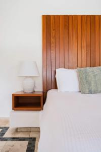 uma cama com uma cabeceira de madeira e um candeeiro sobre uma mesa em Ileverde 21 - Private garden Bungalow em Punta Cana