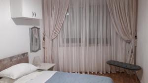 a bedroom with a bed and a window with curtains at LILI50 in Plovdiv