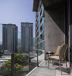 un balcone con 2 sedie e un tavolo su un edificio di Cerca de consulado EUA, nuevo, lujoso en Jardín Secreto 503 a Monterrey