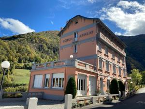 a large pink building with a mountain in the background at Appart Résidence Le Chili - Lit fait - Parc - Quartier thermal in Luz-Saint-Sauveur