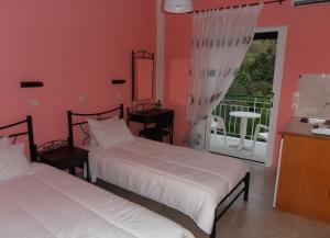 a bedroom with two beds and a balcony at Elenas Garden in Kavos