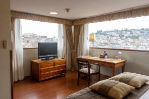 1 dormitorio con escritorio, TV y ventana en Hotel Patio Andaluz, en Quito