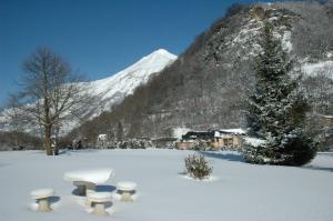 un campo cubierto de nieve con bancos frente a una montaña en Appart Résidence Le Chili - Lit fait - Parc - Quartier thermal, en Luz-Saint-Sauveur