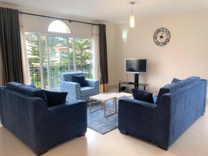 a living room with two blue chairs and a tv at Appartements - Le Paradisier Ambatobe in Antananarivo