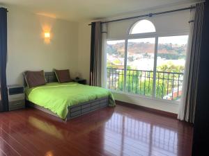 ein Schlafzimmer mit einem grünen Bett und einem großen Fenster in der Unterkunft Appartements - Le Paradisier Ambatobe in Antananarivo