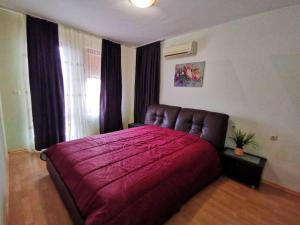 um quarto com uma cama grande e uma colcha vermelha em Villa Aspen Guest House em Primorsko