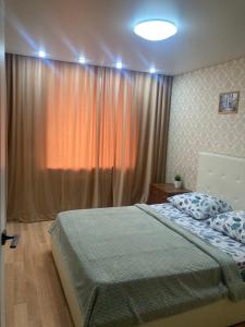 ein Schlafzimmer mit einem Bett und einem großen Fenster in der Unterkunft Apartment on Krasina-Abay street in Öskemen