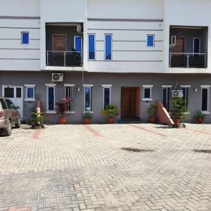 un grand bâtiment avec des fenêtres bleues et un parking dans l'établissement ORCHID House Stylish 3BDR Terrace Duplex Free WiFi DSTV, à Lekki