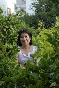 a woman is smiling through a bush at Margarita Studios in Parikia