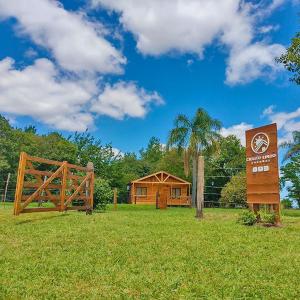 un cartel en un campo junto a un edificio de madera en Cielito Lindo Cabañas en Gualeguay