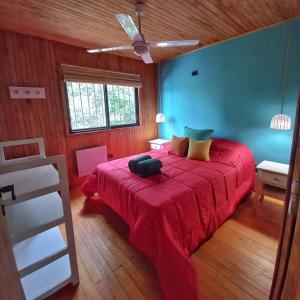 1 dormitorio con cama roja y ventilador de techo en Cielito Lindo Cabañas en Gualeguay