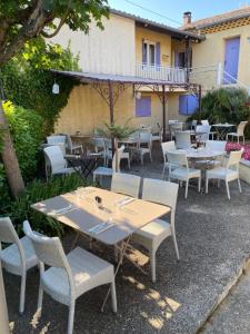 a group of tables and chairs in front of a building at Logis Le Mistral - Montélimar Sud in Châteauneuf-du-Rhône