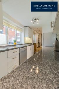 a kitchen with white cabinets and a black counter top at Free Parking, Entire 8 Ensuite Bedroom Townhouse, Fully Equipped Kitchen, Dining Room & Lounge, Perfect for Family Gatherings, Long Term Contractor, Relocation, etc Stays, 15 mins to Nissan, 20 mins to Sunderland & Newcastle, See our Site for Assurance in South Shields