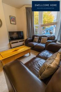 uma sala de estar com sofás de couro e uma televisão em Dwellcome Home Ltd Spacious 8 Ensuite Bedroom Townhouse - see our site for assurance em South Shields