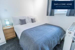 Dormitorio pequeño con cama con manta azul en Dwellcome Home Ltd Spacious 8 Ensuite Bedroom Townhouse - see our site for assurance en South Shields