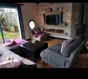 a living room with two couches and a tv at A quelques pas du moulin blanc in Brest