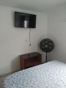 1 dormitorio con 1 cama y TV en la pared en Loft/APTO em Praia da Pinheira, en Pinheira