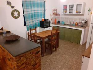 a kitchen with a table and chairs and a microwave at Casa das Violetas - Serra do Cipó in Serra do Cipo