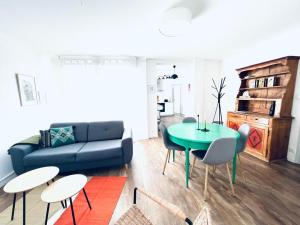 ein Wohnzimmer mit einem blauen Sofa, einem Tisch und Stühlen in der Unterkunft Au perron avec garage et balcon à Ribeauville in Ribeauvillé