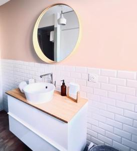 ein Badezimmer mit einem weißen Waschbecken und einem Spiegel in der Unterkunft Au perron avec garage et balcon à Ribeauville in Ribeauvillé