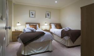 two beds in a bedroom with two lamps and towels at Merewood Lodge in Ambleside